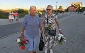 dwie osoby z bukietami kwiat&oacute;w