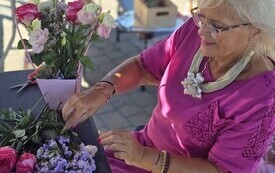 osoba w r&oacute;zowej sukience układajaca kwiaty