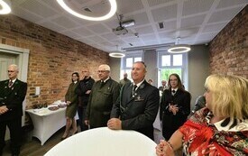 na sali przy białym stoliku stoi grupa ludzi 
