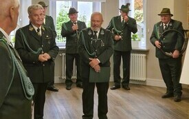 na sali stoi grupa ludzi w mundurach mysliwskich