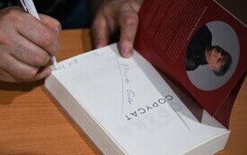 ręka z długopisem podpisujaca książkę