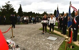osoby składające kwiaty pod pomnikiem