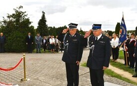 strażacy salutujący pod pomnikiem