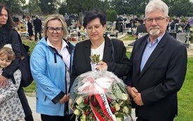 trzy osoby z wiazanką kwiat&oacute;w