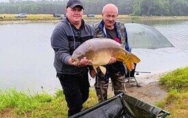 nad brzegiem wody stoja dwaj mężczyźni i trzymają dużą rybę 