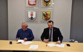 dw&oacute;ch mężczyzn siedzących przy stole przed nimi leżą dokumenty
