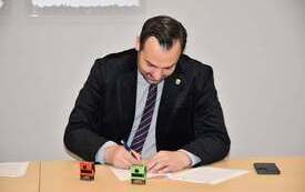 mężczyzna w czarnym garniturze podpisujący dokument