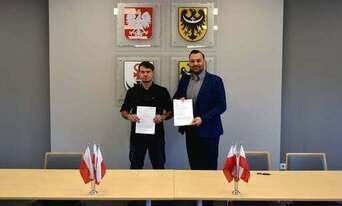dwie osoby stojące w sali i trzymające białe dokumenty