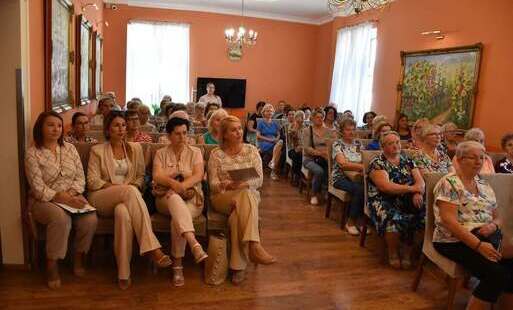 grupa ludzi siedzących na krzesłach w pomarańczowej sali