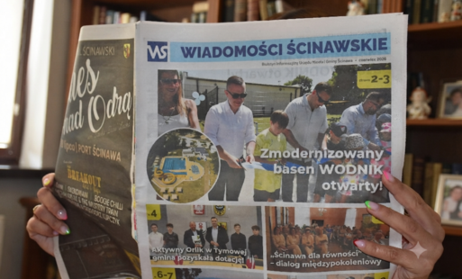 ręce trzymające gazetę wiadomości ścinawskie, w tle widać regał z książkami